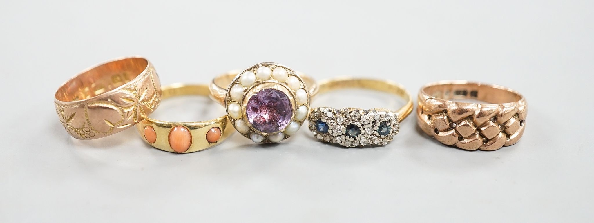 An early 20th century 18ct gold and gypsy set three stone coral ring, size P/Q, a similar sapphire and diamond set triple cluster ring, 5.5 grams, two similar 9ct gold rings, 7.7 grams and a yellow meta, foil backed amet